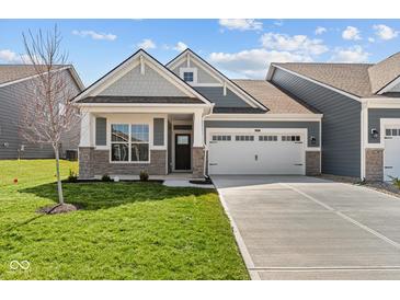 Charming home showcasing stone accents, a manicured lawn, and a spacious two-car garage at 16946 Cattle Hollow Ln, Noblesville, IN 46060