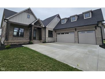 Charming brick home with a three-car garage and covered front porch, complemented by a well-manicured lawn at 16298 Grand Cypress Dr, Noblesville, IN 46060
