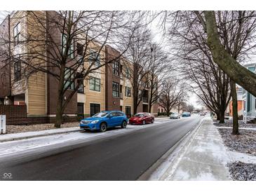 Street view of the apartment complex in winter with a blue car parked in front at 233 E Saint Joseph St # 3E, Indianapolis, IN 46202