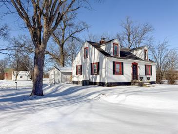 White house with red accents, snowy yard, and detached garage at 4509 Madison Ave, Anderson, IN 46013