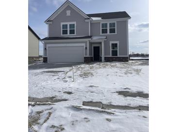 Charming two-story home with a two-car garage, gray siding and a manicured lawn. Snow on the ground at 239 Ambassador Dr, Pittsboro, IN 46167