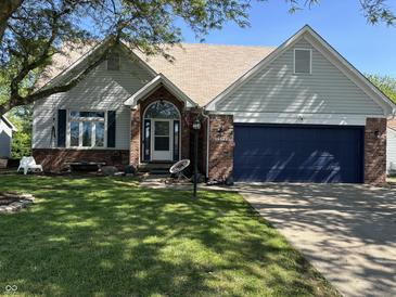 Charming home with a well-manicured lawn, brick accents, and a striking blue garage door at 11720 Grenadier Ln, Indianapolis, IN 46229