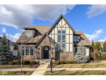 Charming two-story home features a combination of brick and stucco, with a steeply pitched roof and professionally landscaped yard at 520 Bridgemont Ln, Carmel, IN 46032