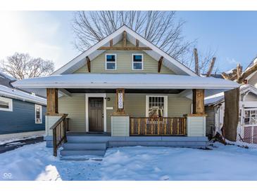 Charming craftsman bungalow with a covered porch and snow-covered lawn at 5009 E Michigan E St, Indianapolis, IN 46201