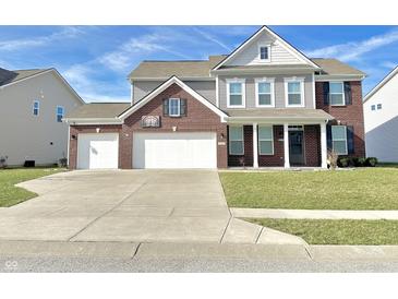 Charming two-story home featuring a brick and siding facade, attached three-car garage, and well-manicured lawn at 5128 Macaferty St, Plainfield, IN 46168