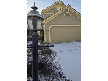 Snow-covered driveway and charming house exterior with a large garage at 6549 Aintree Ter, Indianapolis, IN 46250