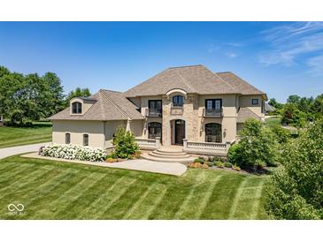Stately tan two-story home boasts stone accents, manicured lawn, and beautiful landscaping at 1023 Westview Point Dr, Columbus, IN 47201
