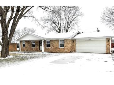 Brick ranch home with attached garage, snowy front yard, and mature trees at 2006 E 44Th St, Anderson, IN 46013