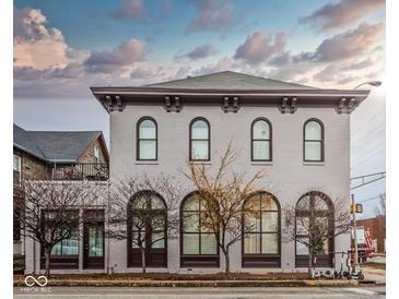 Charming building featuring a light brick facade, arched windows, and classic architectural details under a cloudy sky at 304 N College Ave # Apt B, Indianapolis, IN 46202