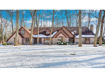 Brick home with snow-covered lawn, nestled among tall trees at 7425 Cherryhill Dr, Indianapolis, IN 46254