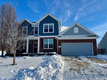 Two-story home with brick and blue siding, snowy front yard, and attached garage at 13229 Isle Of Man Way, Fishers, IN 46037