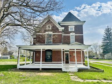Charming two-story brick home featuring a welcoming wrap-around porch and detailed architectural accents at 503 S Harrison St, Alexandria, IN 46001