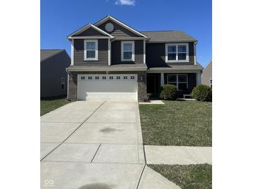 Charming two-story home featuring a spacious driveway, two-car garage, and well-maintained lawn under a clear blue sky at 6232 Emerald Springs Dr, Indianapolis, IN 46221