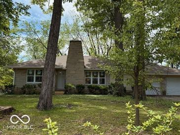 Charming one-story home featuring a stone chimney and a well-maintained front lawn with mature trees at 4621 E 37Th St, Indianapolis, IN 46218