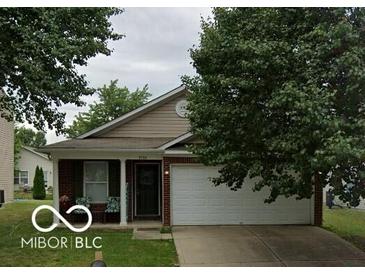 Beige house with a white garage door and landscaping at 9750 Jackson Way, Avon, IN 46123