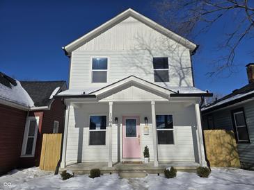 Two-story white house with pink door, covered porch, and snow-covered yard at 1306 E Minnesota St, Indianapolis, IN 46203