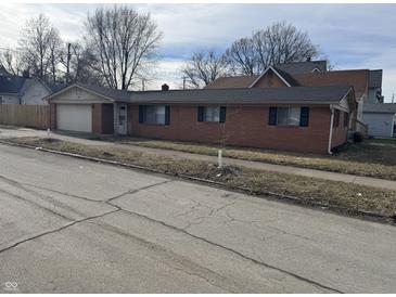 Charming brick home featuring an attached garage and well-maintained front yard at 1801 W Morris St, Indianapolis, IN 46221