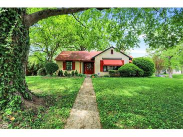 Charming home with lush green lawn, mature tree, and welcoming walkway to the front door at 6072 Meridian St W Dr, Indianapolis, IN 46208
