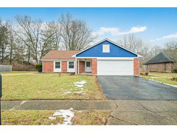 Charming brick home with a blue accent, attached garage, and driveway at 7817 Dartmouth Rd, Indianapolis, IN 46260