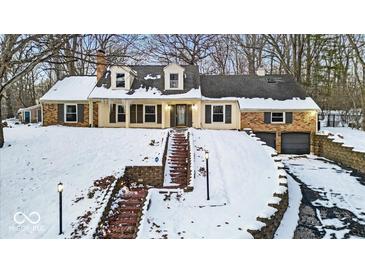 Brick home with snow covered landscaping and a large driveway at 9210 Briarclift Rd, Indianapolis, IN 46256