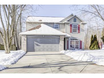 Two-story house with gray siding, red shutters, and a gray garage door, covered in snow at 5334 Thrasher Dr, Indianapolis, IN 46254