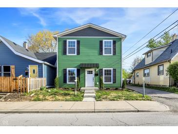 Charming two-story home featuring a vibrant green exterior with black shutters and a well-maintained front yard at 1446 E Naomi St, Indianapolis, IN 46203