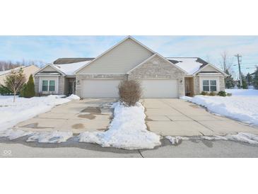 Tan brick ranch home with two-car garage and snow-covered driveway at 2367 Heartland Ln, Brownsburg, IN 46112