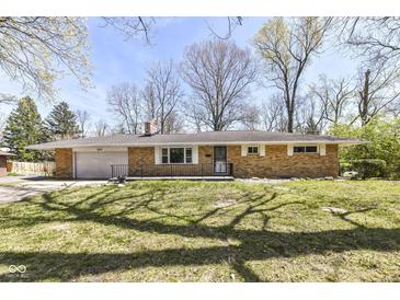 Charming single-story brick home with attached garage, front porch and mature trees and landscaping at 3375 Lincoln Rd, Indianapolis, IN 46222