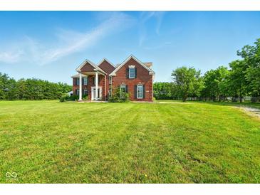 Stately red brick home boasts beautiful columns, a manicured lawn, and charming curb appeal at 4450 W 300 N, Fairland, IN 46126