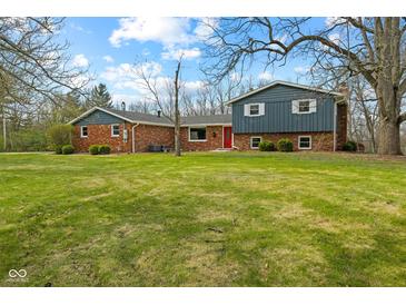 Charming brick home with blue siding, a bright red front door, and a spacious front lawn at 8810 W Tulip Tree Dr, Muncie, IN 47304