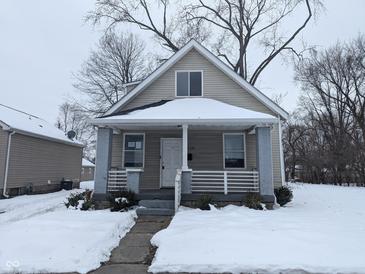 Tan house with white trim and porch, nestled on a snow-covered lot at 1128 N Holmes Ave, Indianapolis, IN 46222