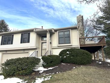 Beige exterior home with a deck, landscaping, and attached garage at 9518 Bay Vista E Dr, Indianapolis, IN 46250