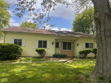 Charming single-story home featuring a landscaped front yard and light yellow siding at 208 Winding Dr, Alexandria, IN 46001