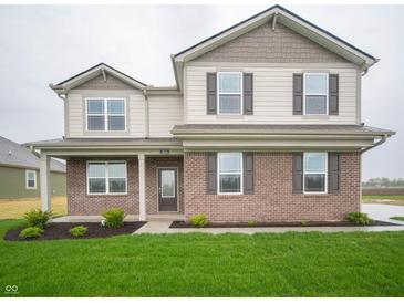 Charming two-story home featuring a brick facade, landscaped yard, and welcoming front porch at 7824 Magnolia St, New Palestine, IN 46163