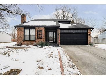 Brick ranch home with a black garage door and snow-covered landscaping at 9451 Falkirk Dr, Indianapolis, IN 46256