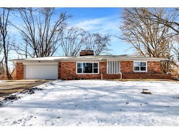 Brick ranch home with a snow-covered lawn and attached garage at 8408 Valley Estates Dr, Indianapolis, IN 46227