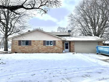 Brick ranch home with attached garage, nestled on a snow-covered lot at 9157 Neptune Dr, Indianapolis, IN 46229