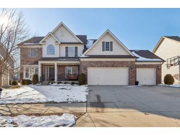 Charming two-story home featuring a brick and siding facade, a three-car garage, and a welcoming front porch at 14928 Declaration Dr, Westfield, IN 46074