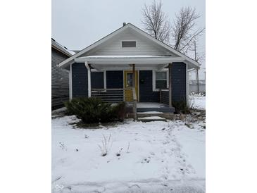 Cute bungalow with blue siding, white trim, and a yellow door at 239 Iowa St, Indianapolis, IN 46225