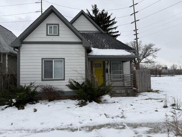 Charming white house with gray accents, yellow door, and snowy yard at 243 E Caven St, Indianapolis, IN 46225