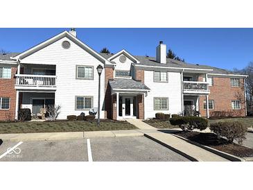 Traditional condo building featuring brick accents, white siding, private balconies, and well-kept landscaping at 8104 Glenwillow Ln # 208, Indianapolis, IN 46278