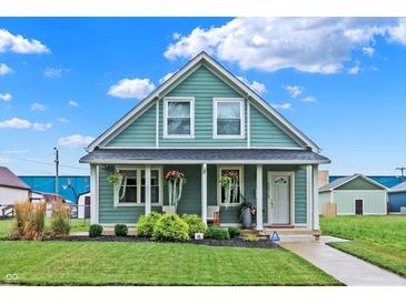 Charming teal house with a covered porch and well-manicured lawn at 2015 Columbia Ave, Indianapolis, IN 46202