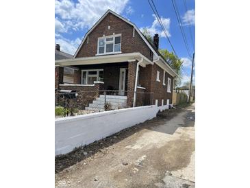 Brick home with front porch, steps, and a white wall at 448 N Gray St, Indianapolis, IN 46201