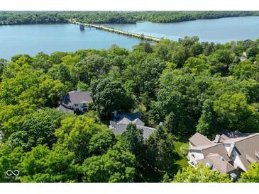 An aerial view of a luxury home surrounded by lush greenery, near a scenic lake with a bridge at 5508 Bay Landing Cir, Indianapolis, IN 46254