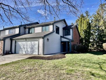 Charming two-story home with attached garage and freshly manicured lawn on a sunny day at 8207 Shorewalk Dr, Indianapolis, IN 46236