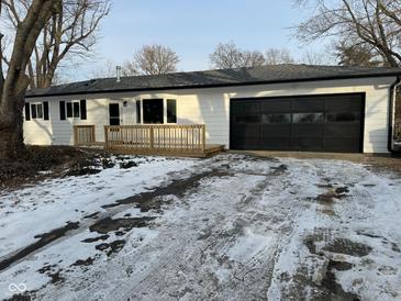 White ranch home with black garage door, wooden deck, and snow-covered yard at 1908 N Duane Rd, Muncie, IN 47304