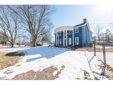 Blue house with white columns, snow on the ground, and a chain link fence at 4042 E Clover St, Columbus, IN 47203