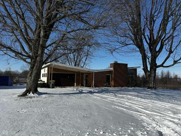 Brick ranch home with attached garage, nestled on a snow-covered lot at 1623 Sherwood Dr, Anderson, IN 46012