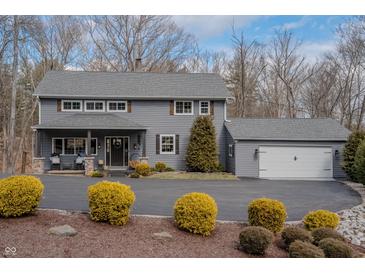 Charming two-story home boasts a well-manicured lawn, attached garage, and welcoming front porch at 8850 W State Road 46, Columbus, IN 47201