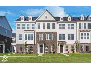 Three-story townhome with brick and siding exterior, featuring a welcoming front yard at 14569 Hanford Ln, Carmel, IN 46032